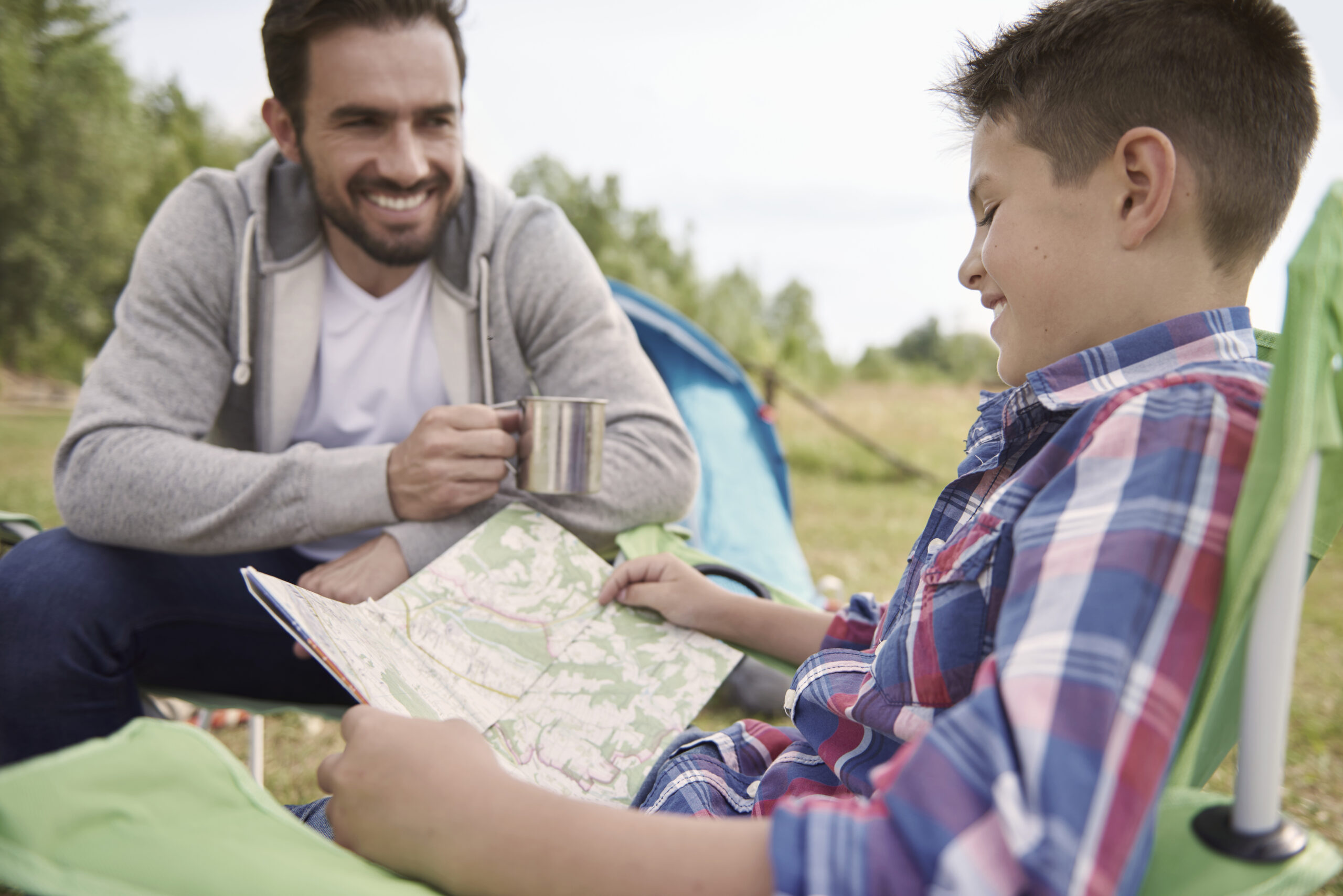 Monitor de ocio y tiempo libre ayudando a un joven a interpretar un mapa durante actividad educativa al aire libre