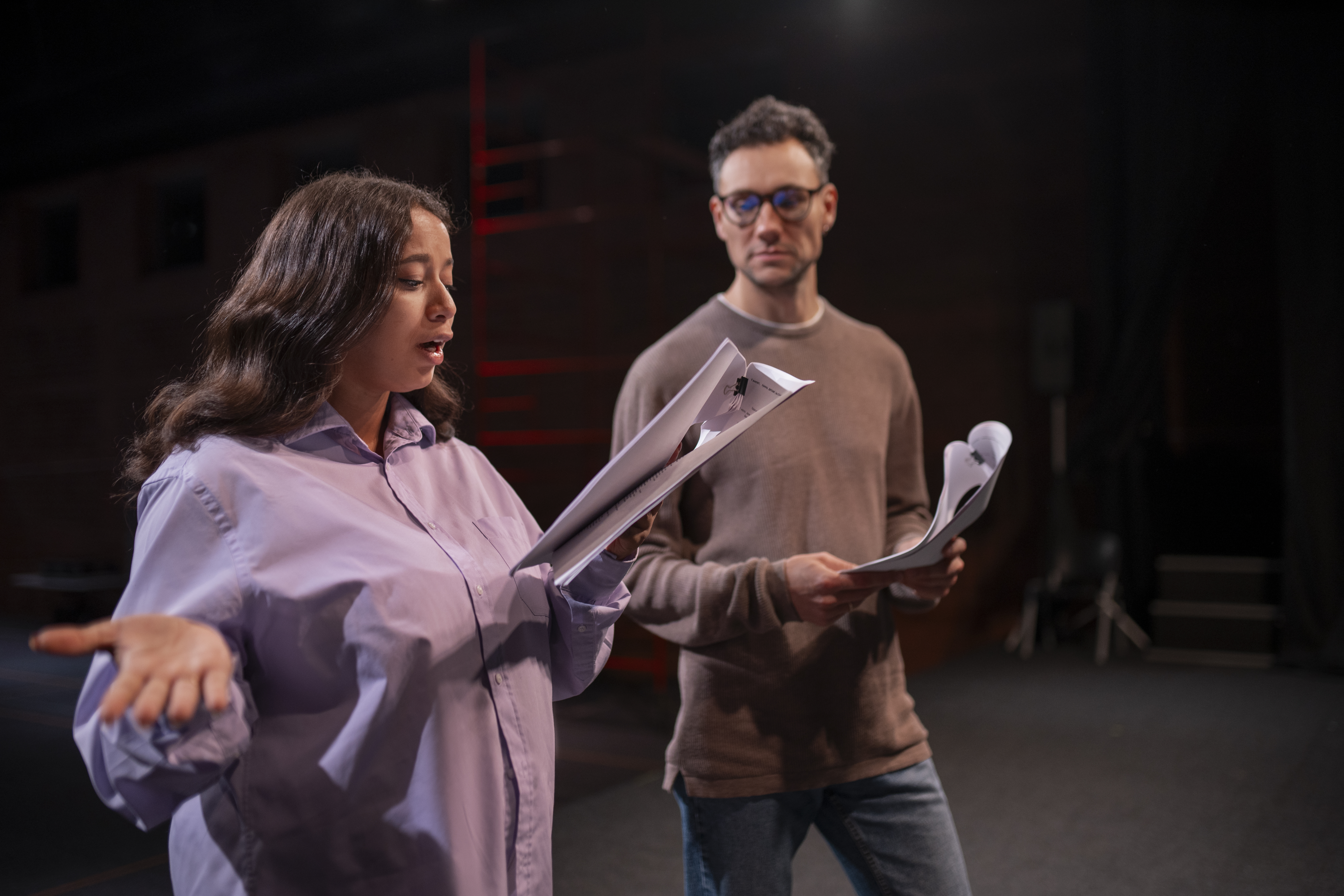 Personas ensayando una escena teatral con guion en una actividad educativa.