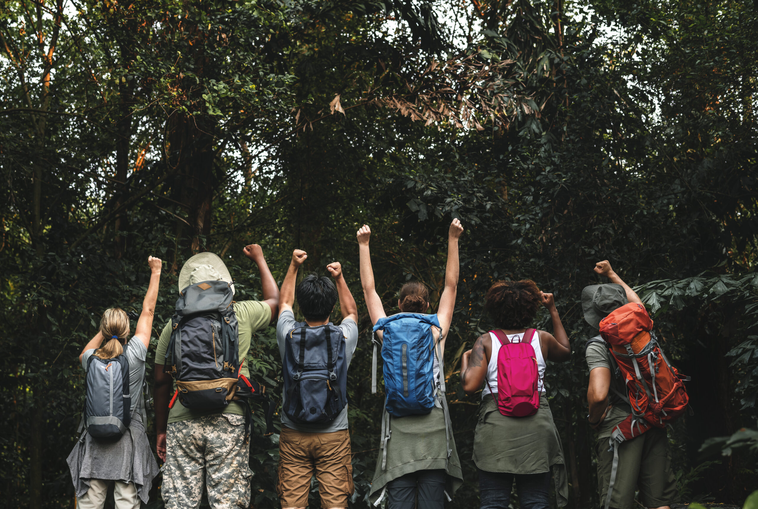 Grupo de jóvenes con mochilas participando en actividad de campamento en la naturaleza con monitores de ocio educativo