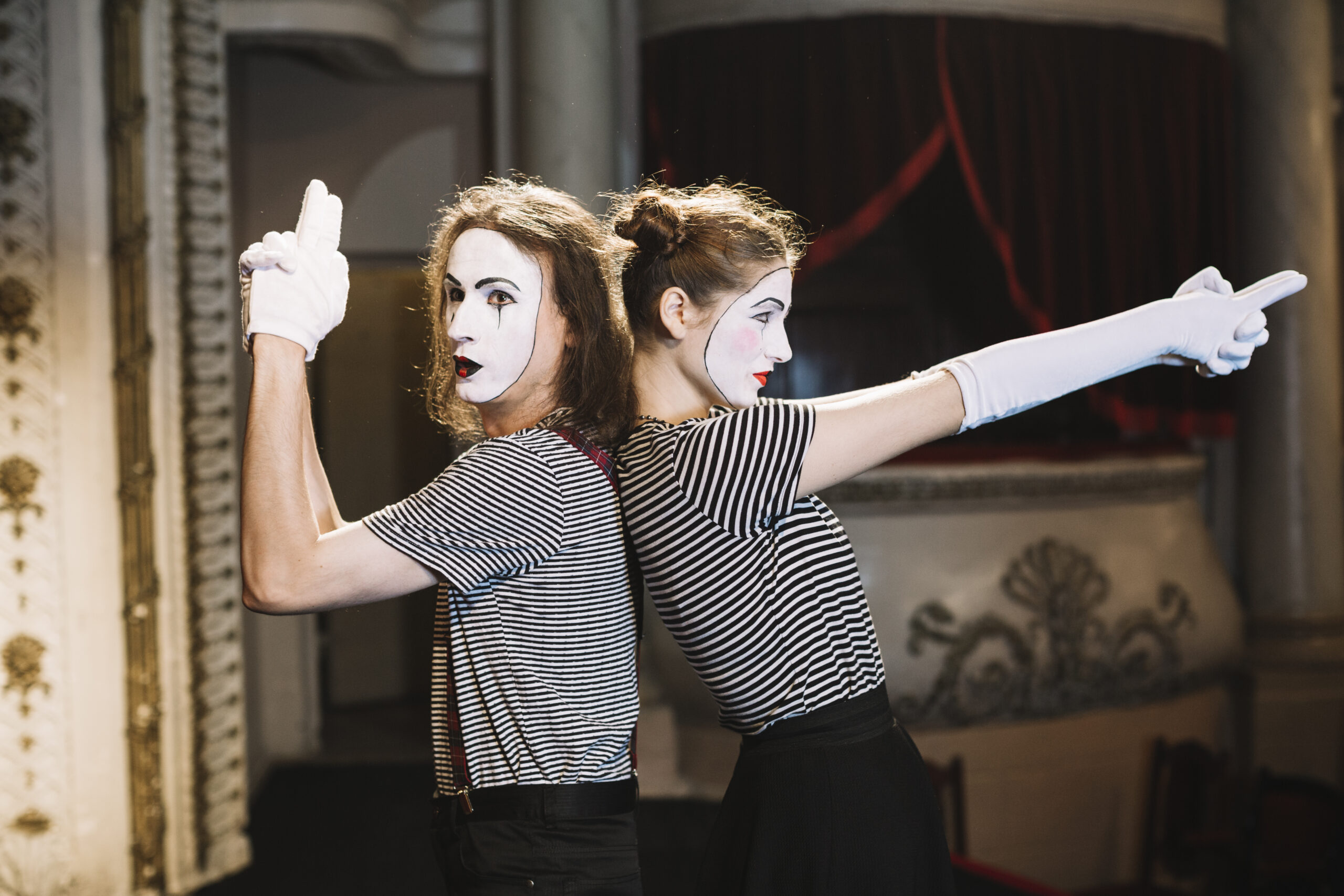 Personas caracterizadas como mimos realizando una actividad teatral en grupo.