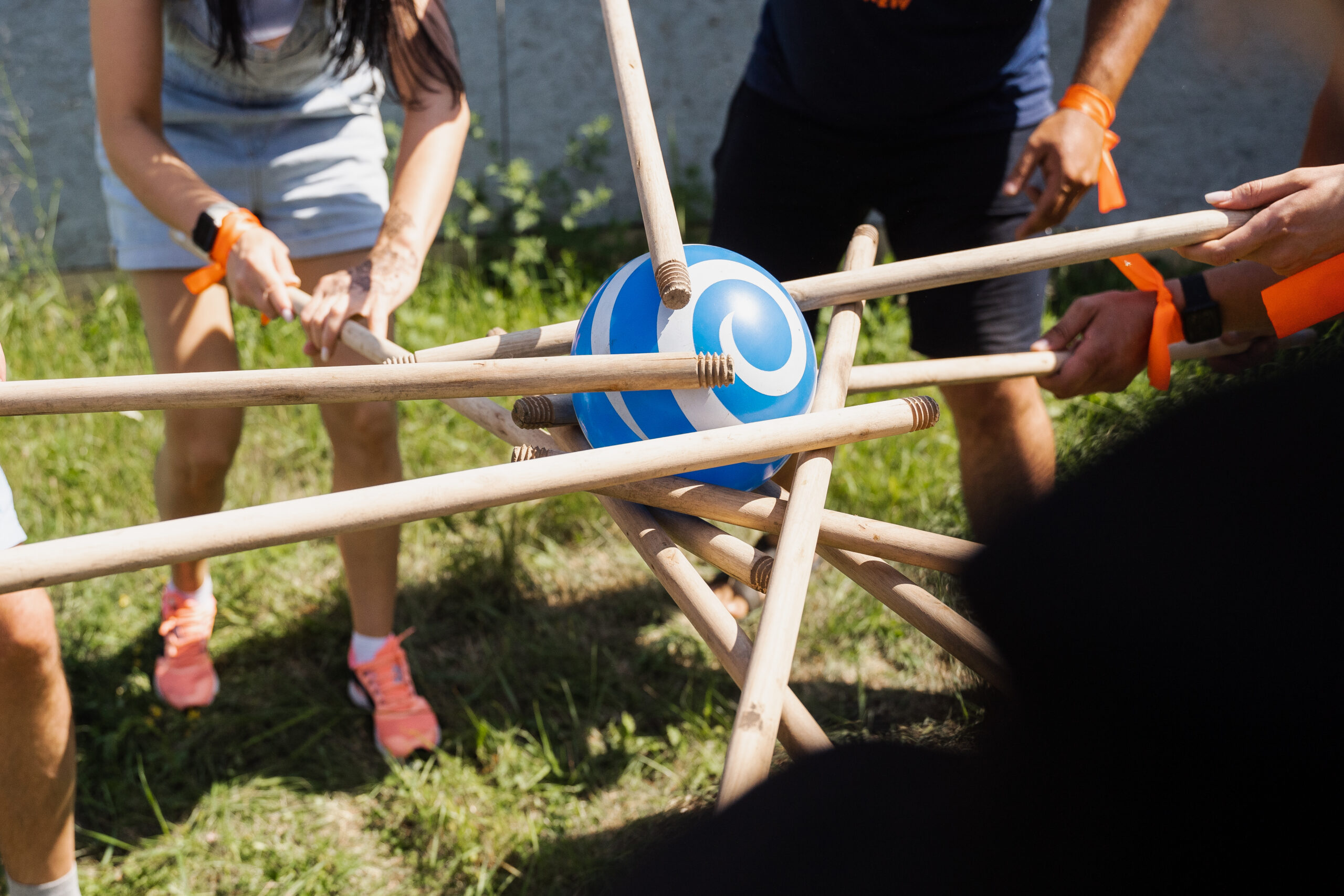 Grupo de personas realizando un juego de equipo con palos y una pelota durante una gymkhana al aire libre.