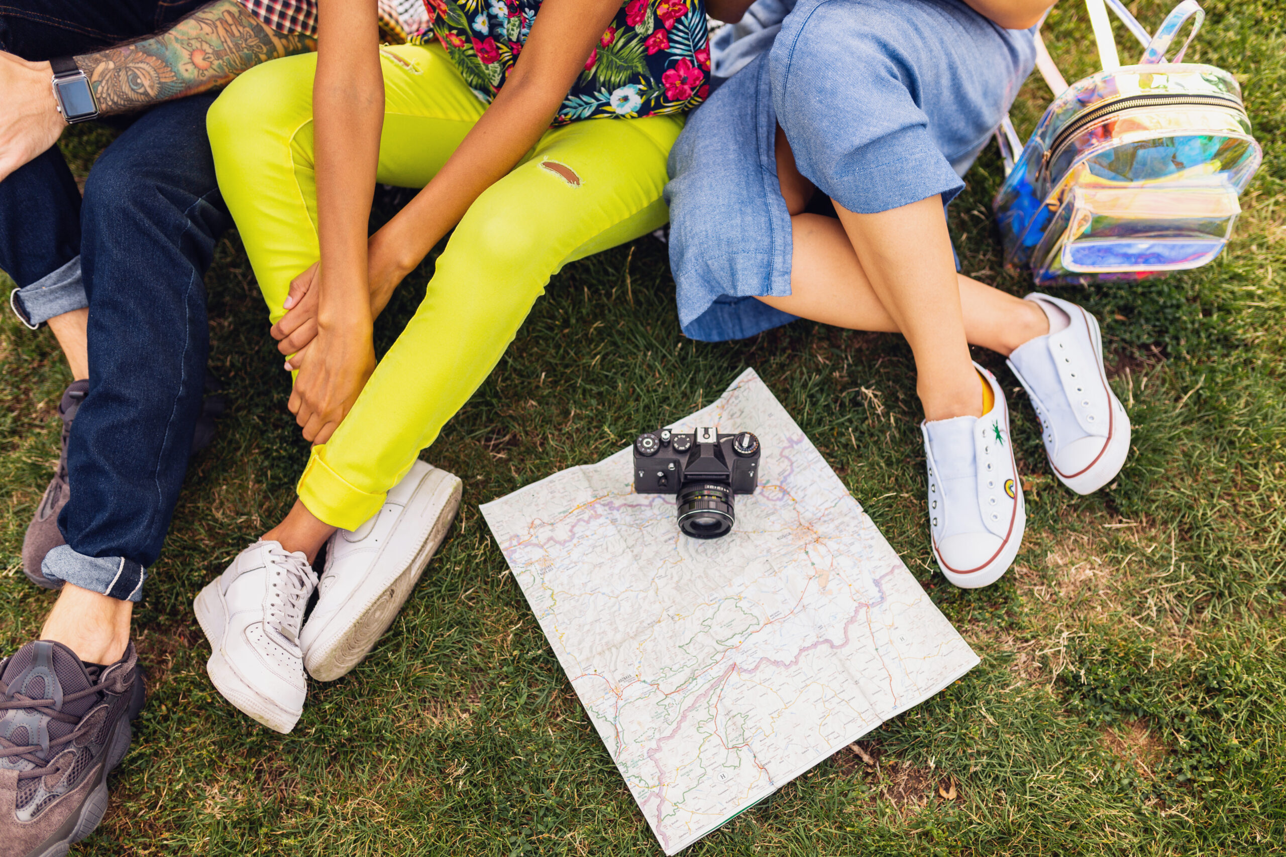 Jóvenes sentados en el césped con un mapa y una cámara durante una actividad al aire libre