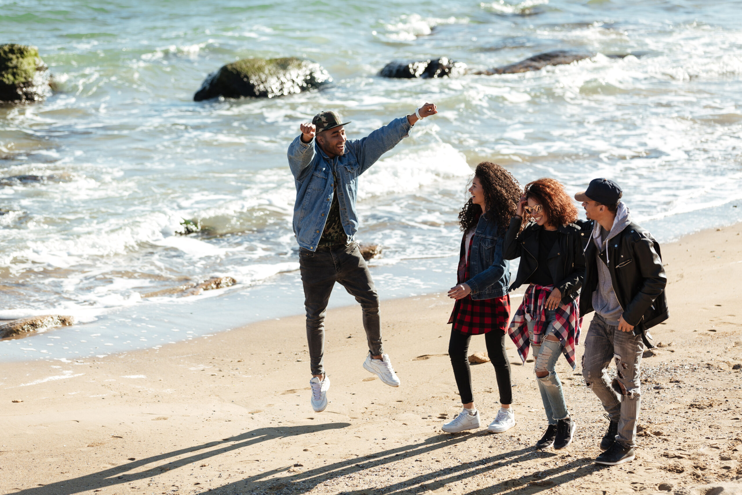Grupo de estudiantes disfrutando y caminando por la playa durante un viaje de fin de curso.
