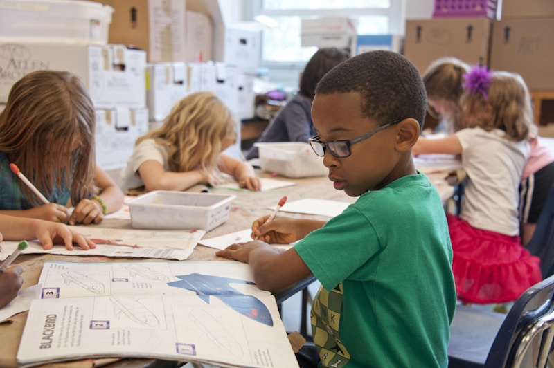 Niños realizando actividades educativas y dibujos en un aula escolar infantil.